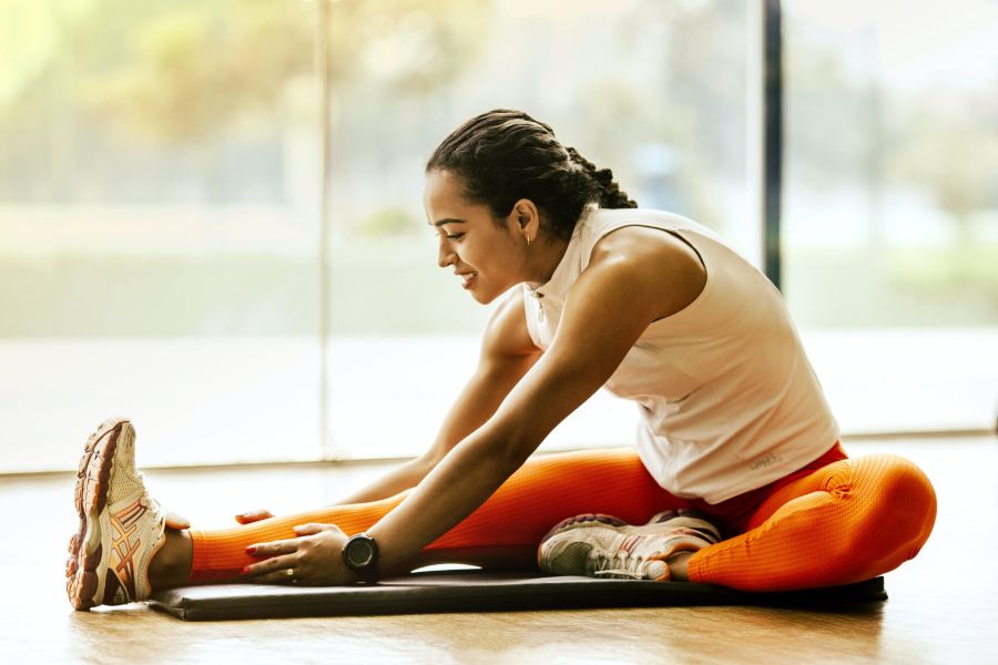 Vrouw rekt zich uit op een yogamat