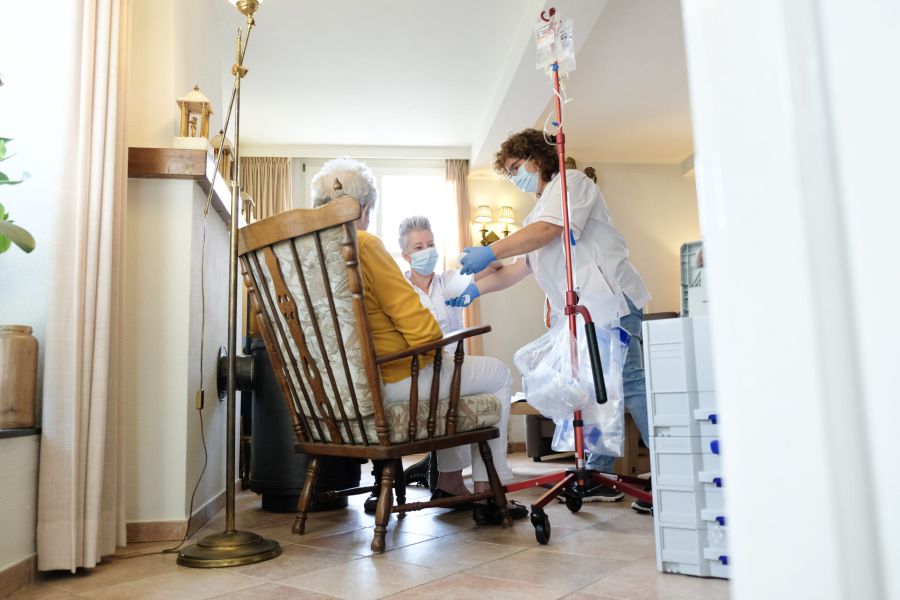 oude vrouw word geholpen door zorgverlener