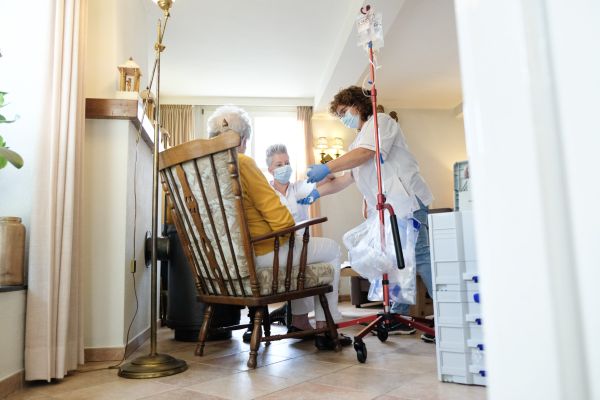 oude vrouw word geholpen door zorgverlener